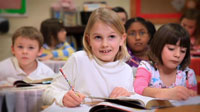 Girl smiling while working on homework in classroom