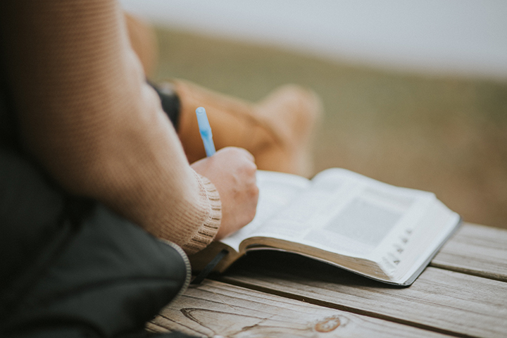 person making notes in a Bible